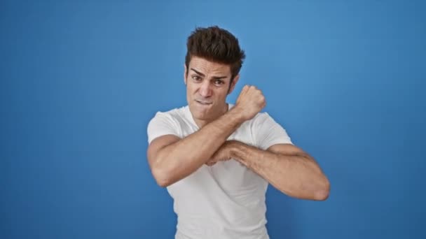 Jeune homme hispanique faisant geste majeur sur fond bleu isolé - Séquence, vidéo