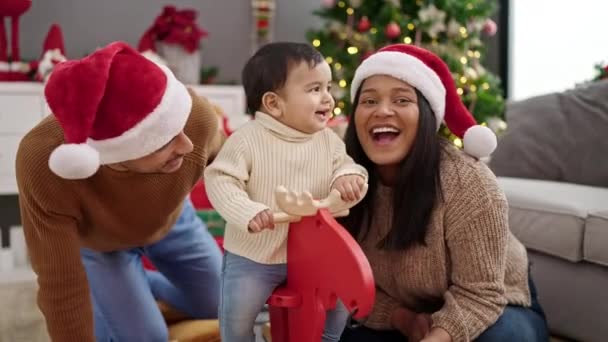 Ζευγάρι και γιος παίζουν με τάρανδους λικνίζονται από χριστουγεννιάτικο δέντρο στο σπίτι - Πλάνα, βίντεο