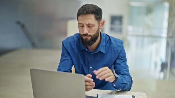 Genç İspanyol iş adamı akıllı telefon ve dizüstü bilgisayar kullanıyor. Ofiste stresli. - Video, Çekim
