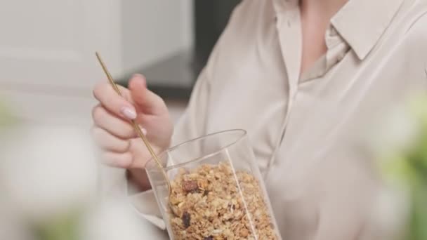 Όμορφη νεαρή Καυκάσια γυναίκα ετοιμάζει υγιεινό πρωινό granola στο σπίτι το Σαββατοκύριακο - Πλάνα, βίντεο
