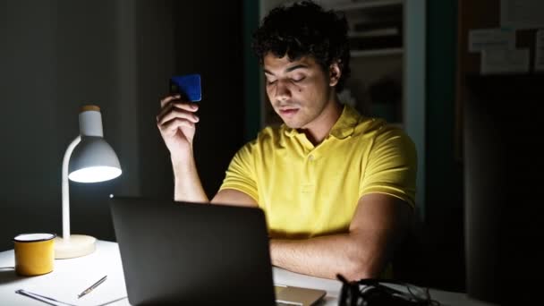 Joven trabajador de negocios latino de compras con computadora portátil y tarjeta de crédito en la oficina - Imágenes, Vídeo