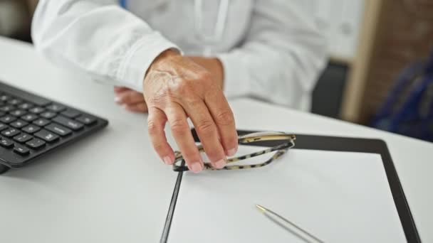 Μεσήλικας Ισπανίδα γιατρός που χρησιμοποιεί υπολογιστή φορώντας γυαλιά στην κλινική - Πλάνα, βίντεο