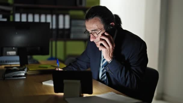 Middelbare leeftijd man zakenman praten op smartphone het maken van notities op kantoor - Video