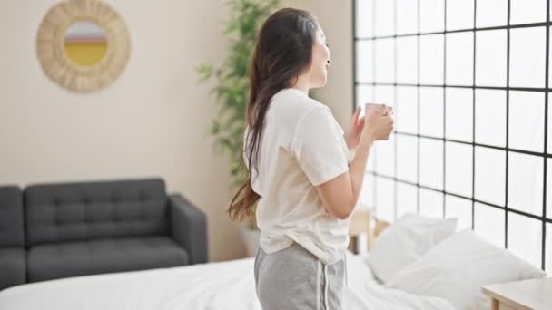 Joven hermosa mujer hispana bebiendo taza de café bailando en el dormitorio - Metraje, vídeo