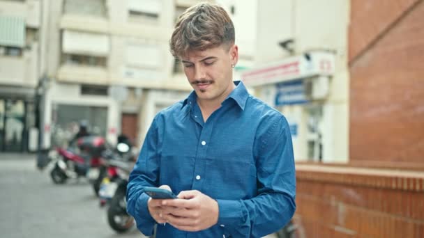 Jonge Spaanse man met smartphone met winnaar gebaar op straat - Video