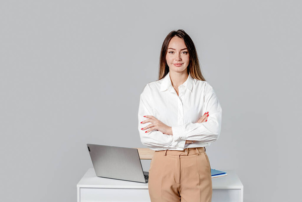 senhora de negócios caucasiana em camisa branca com as mãos dobradas na mesa de escritório isolado em fundo cinza - Foto, Imagem