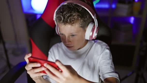 Schattige blonde jongen streamer vol vertrouwen streaming video game op smartphone bij gaming room binnen! schattig kind gamer 's opgewonden nacht thuis entertainment. - Video