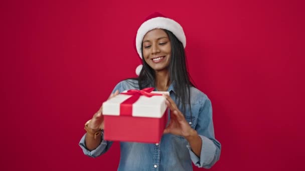 Femme afro-américaine tenant cadeau de Noël sur fond rouge isolé - Séquence, vidéo