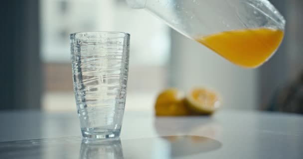 グラスにオレンジジュースを注ぐ背景のスローモーションビデオ. 朝食のために自宅のキッチンで新鮮なジュース. 高品質の4k映像 - 映像、動画