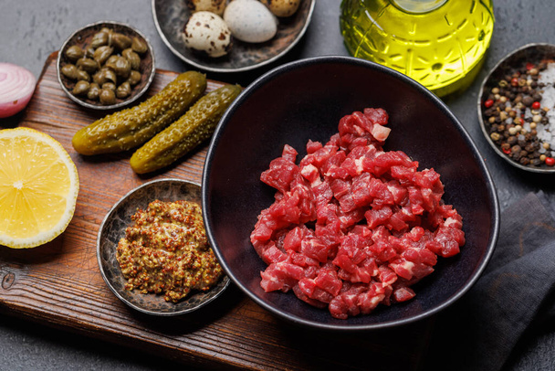 Cooking savory beef tartare with pickled gherkins and brown bread toasts - Photo, Image