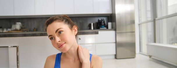 Detailní portrét mladé ženy dělá fitness doma, dotýká se krku, masíruje ramena po tréninku. Pojem pohody a sportu - Fotografie, Obrázek