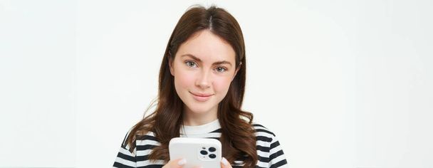 Porträt einer Frau, die ihre Nachrichten auf dem Handy checkt und auf den Smartphone-Bildschirm blickt. - Foto, Bild