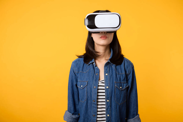 Aziatische jonge vrouw krijgen ervaren het dragen van virtual reality headset game entertainment geïsoleerd op gele achtergrond. Winnaar van cyber toekomstige video game concept. - Foto, afbeelding