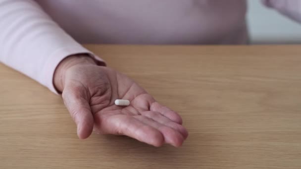In dieser Großaufnahme hält die verwitterte und doch anmutige Hand einer älteren Frau ein paar Tabletten in der Hand. Die Linien auf der Haut verraten ein Leben voller Geschichten, und in der Hand hält sie die Essenz des Wohlbefindens. - Filmmaterial, Video