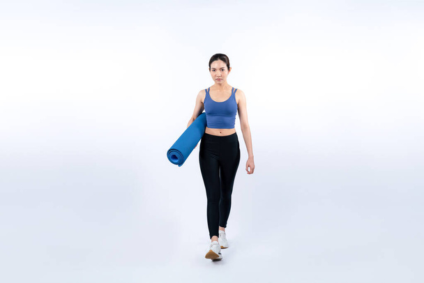 Mladá atraktivní asijská žena portrét ve sportovním oblečení s podložkou na cvičení. Zdravé cvičení a cvičení rutinní životní styl koncepce. Studio natočilo izolované pozadí. Silný - Fotografie, Obrázek