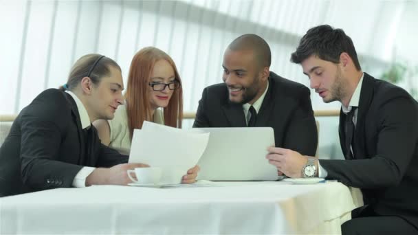Lachende zakenman in een vergadering. Zakelijke ontmoeting met collega's. Vier lachende succesvolle zakenlui zittend aan tafel in kantoor. - Video
