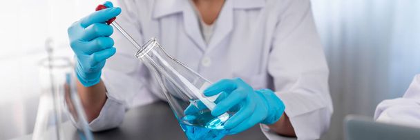 Naukowiec przeprowadzić eksperyment chemiczny w laboratorium medycznym, ostrożnie wrzucić dokładną ilość płynu z pipety do probówki na lek szczepionkowy lub rozwój antybiotyków. Neoterynowy - Zdjęcie, obraz