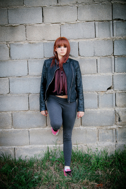 Rebellious teenager girl with red hair leaning on a wall - Photo, Image