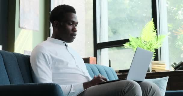 Een ijverige Afro-Amerikaanse ondernemer houdt een videoconferentie vanuit het comfort van het thuiskantoor. Zijn professionele houding en aanpassingsvermogen stralen door als hij contact maakt met collega 's. - Video