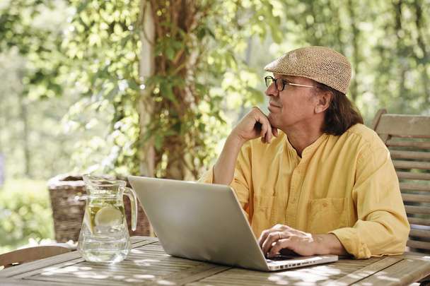 Vanhempi mies ulkona kannettavan tietokoneen kanssa
 - Valokuva, kuva