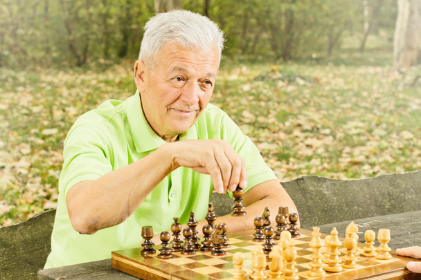 Elderly man playing chess in the park - Photo, image