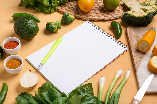 Composition with blank recipe book, fresh vegetables and spices on yellow background - Photo, Image