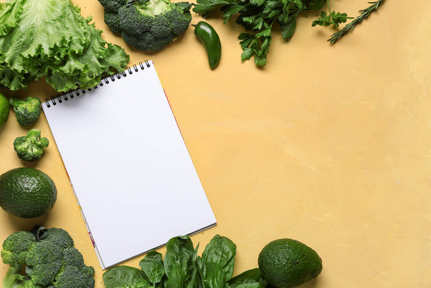 Composition with blank recipe book, fresh vegetables and herbs on yellow background - Photo, Image