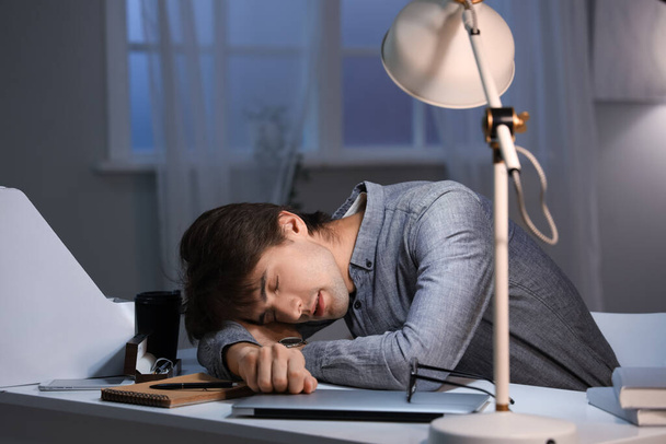 Ύπνος νεαρός επιχειρηματίας που εργάζεται στο γραφείο τη νύχτα - Φωτογραφία, εικόνα