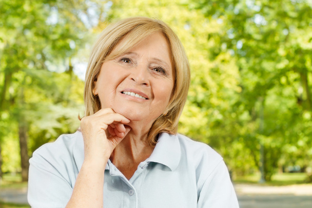 Portrait of smiling senior woman in the park - Foto, immagini