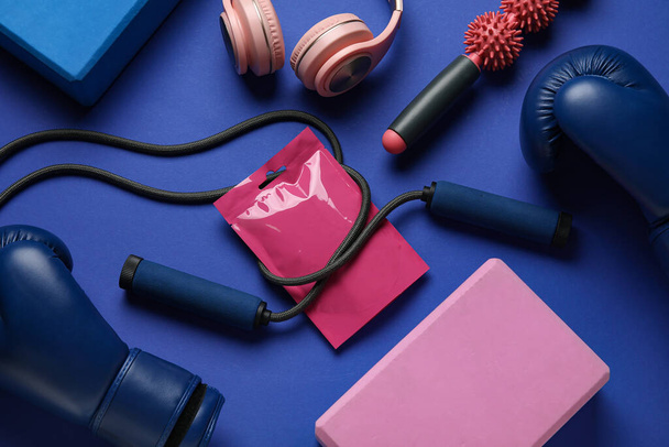 Σύνθεση με τσάντα με σνακ, αθλητικό εξοπλισμό και ακουστικά σε μπλε φόντο - Φωτογραφία, εικόνα