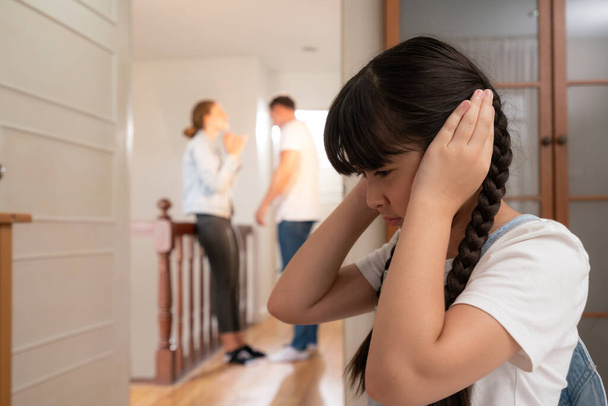 Stresli ve mutsuz genç kız köşeye kıvrılıp kulaklarını kapatarak arka planda ebeveyninin tartışmasını engelliyor. Evde aile içi şiddet ve travmatik çocukluk depresyona dönüşür. Eşzamanlama - Fotoğraf, Görsel