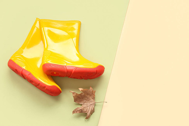 Žluté gumáky s podzimním listem na barevném pozadí - Fotografie, Obrázek