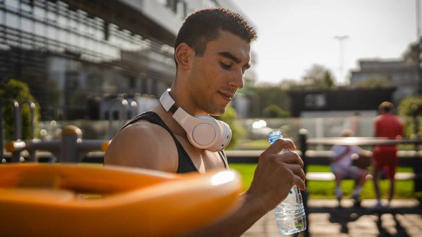 one man caucasian male athlete hold plastic bottle of water opening and prepare to drink while training outdoor in sunny day hydration and healthy lifestyle concept copy space - Fotó, kép