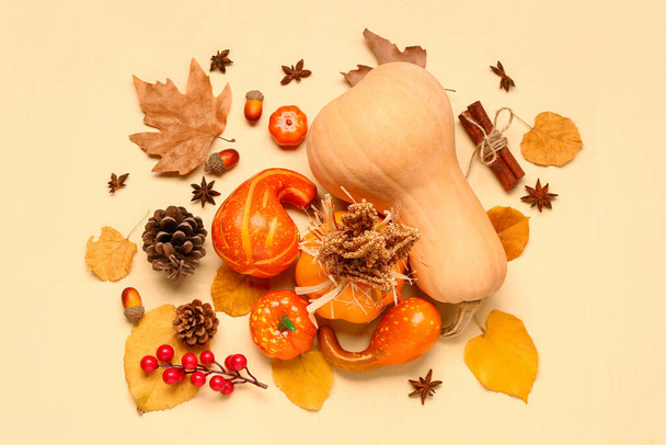 Jesienny skład z dojrzałymi dyniami, jagodami, przyprawami i opadłymi liśćmi na beżowym tle - Zdjęcie, obraz