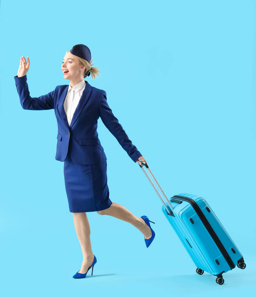 Jeune hôtesse avec valise sur fond bleu - Photo, image