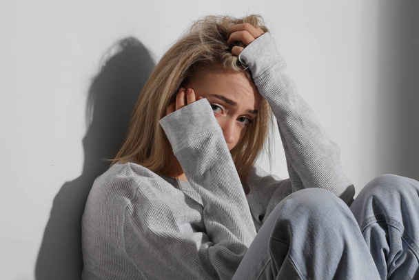 Depressive junge Frau sitzt im Flur, Nahaufnahme - Foto, Bild