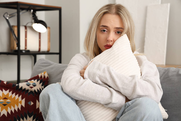 Depresja młoda kobieta z poduszką siedzi na kanapie w domu - Zdjęcie, obraz