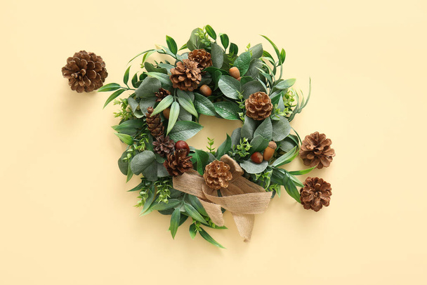 Christmas mistletoe wreath with cones and acorns on yellow background - Photo, Image
