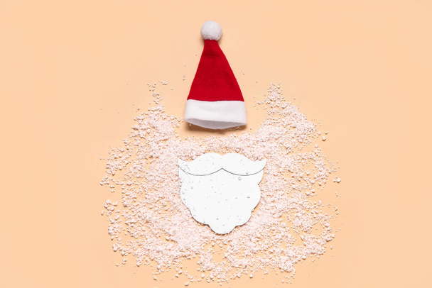 Kompozice s kloboukem Santa, papírovým vousem a sněhem na barevném pozadí - Fotografie, Obrázek
