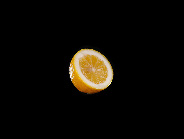 Studio shot of sliced and whole lemons on black background - Φωτογραφία, εικόνα