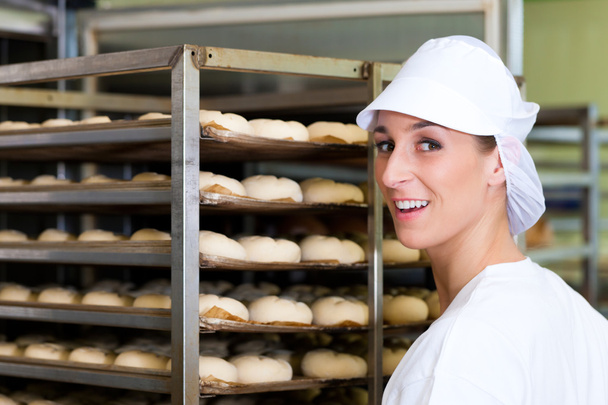 女性のパン屋がパンを焼くロールします。 - 写真・画像