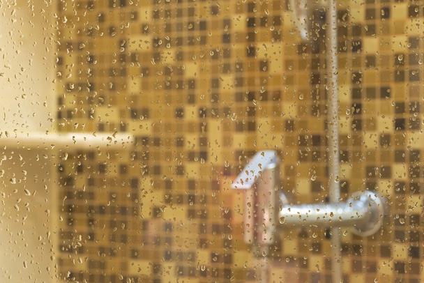 Punho de chuveiro embaçado abstrato com gotas na água sobre a porta da grama em foco
 - Foto, Imagem