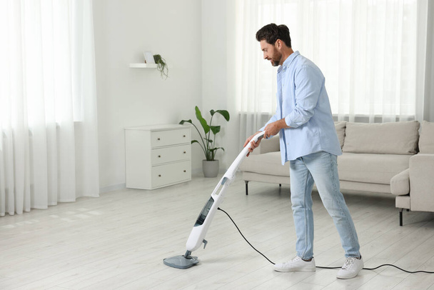 Man cleaning floor with steam mop at home. Space for text - Φωτογραφία, εικόνα