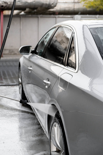 Luxe zilverkleurige auto wassen op touchless car wash. Wassedan auto met schuim self-service en hoge druk water. Het schoonmaken van de gegevens van de auto. Hygiëne en orde in het stedelijk milieu - Foto, afbeelding