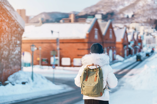 Mujer turista Visitando en Hakodate, Viajero en suéter turismo Kanemori Red Brick Warehouse con nieve en invierno. hito y popular para las atracciones en Hokkaido, Japón.Viajes y concepto de vacaciones - Foto, Imagen