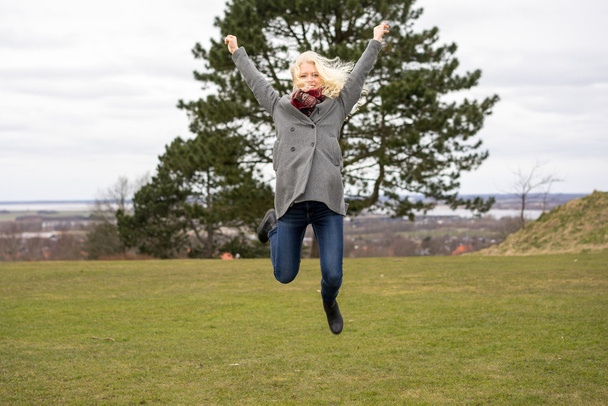 menina loira pulando alegremente
 - Foto, Imagem