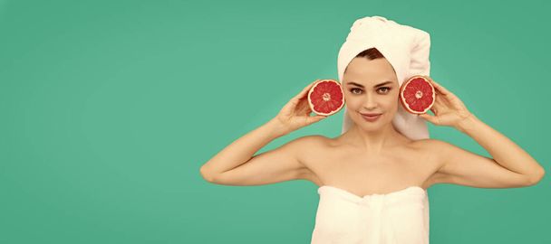 молодая женщина в полотенце после душа с грейпфрутом на синем фоне. Концепция цвета лица. Одинокий портрет женщины, баннер с насмешкой над копирайтом - Фото, изображение
