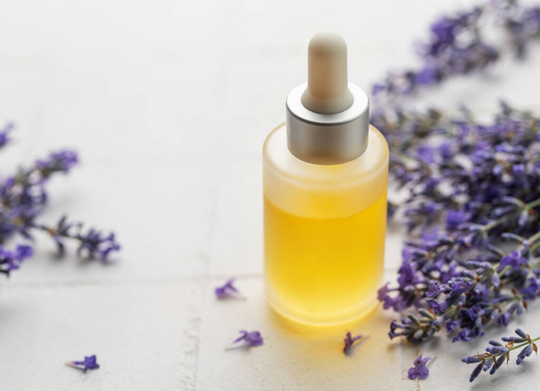 Lavender spa. Lavender  natural essential oil and fresh lavender on a white tile background. - Photo, Image