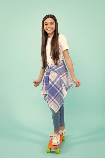 Tiener meisje 12, 13, 14 jaar oud met skateboard over studio achtergrond. Leuke moderne tiener in stijlvolle kleding. Tieners levensstijl, informele jeugd cultuur. gelukkig tiener - Foto, afbeelding