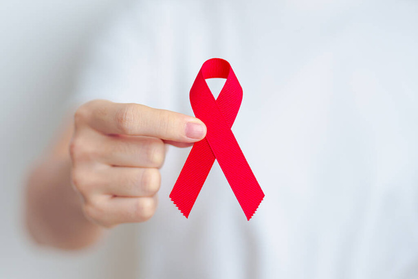 nainen, jolla on punainen nauha joulukuussa Maailman aids päivä, hankittu immuunikato oireyhtymä, multippeli myelooma Cancer Awareness kuukausi ja National Red nauha viikko. Terveydenhuolto ja maailman syöpä päivä käsite - Valokuva, kuva
